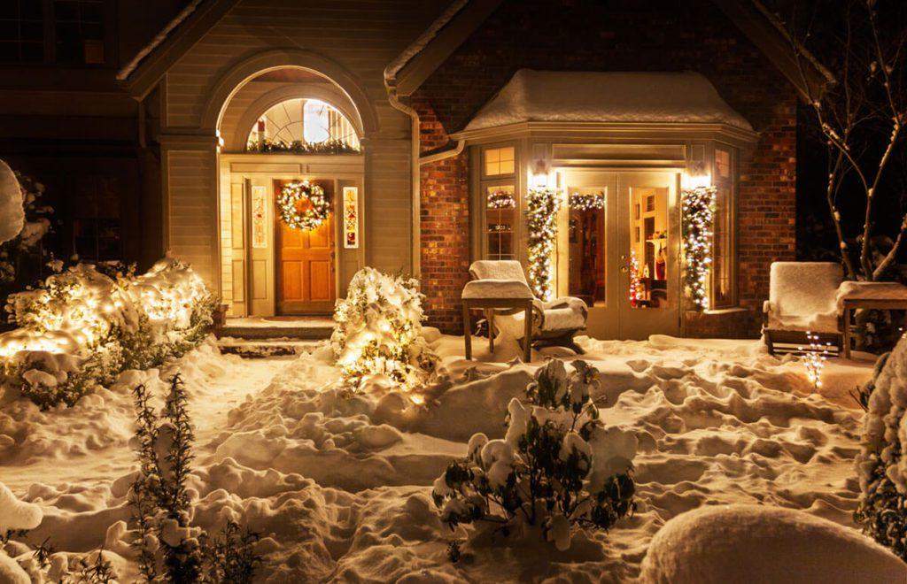 Home front entrance on a snowy night decorated for Christmas