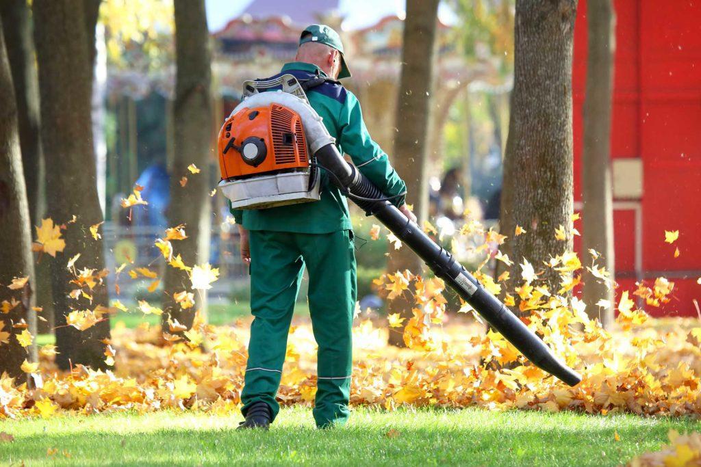 man-blowing-leaves-away-with-leaf-blower man-blowing-leaves-away-with-leaf-blower